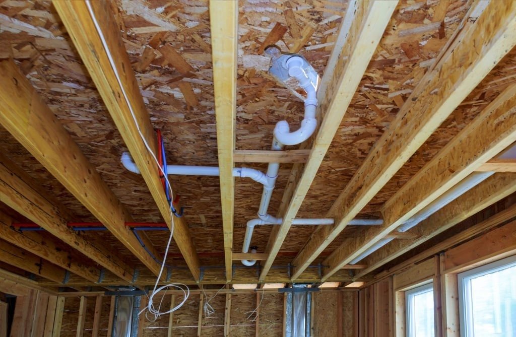 Residential plumbing pipes installed between floor joists in an Elbert home.