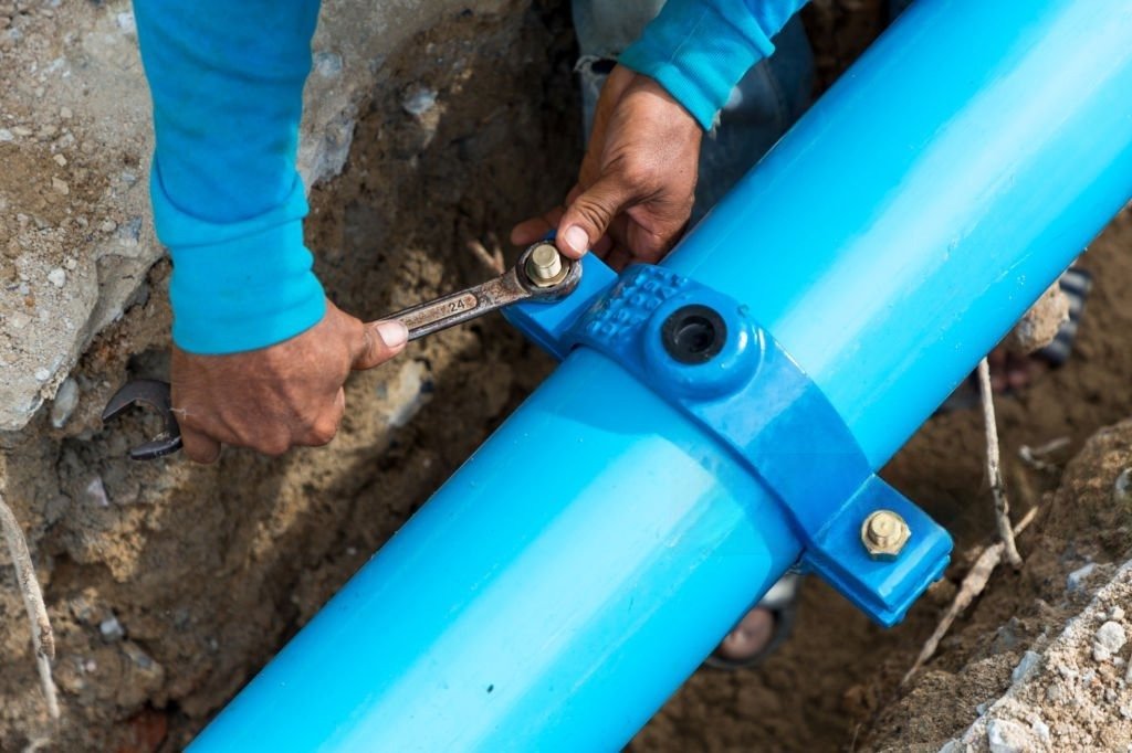 Technician working on an underground pipe connection for trenchless sewer repair in Calhan.