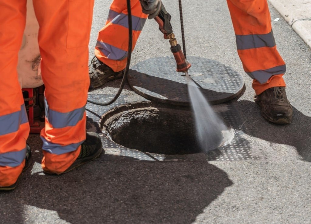 Technicians using high-pressure hydro jetting equipment to clean a sewer access point in Palmer Lake.