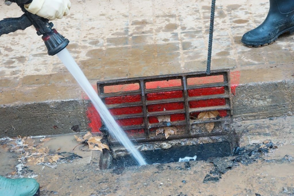 Technician using high-pressure hydro jetting equipment to clear an outdoor drain in Kiowa.